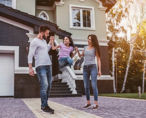 Happy couple swinging their daughter in the driveway